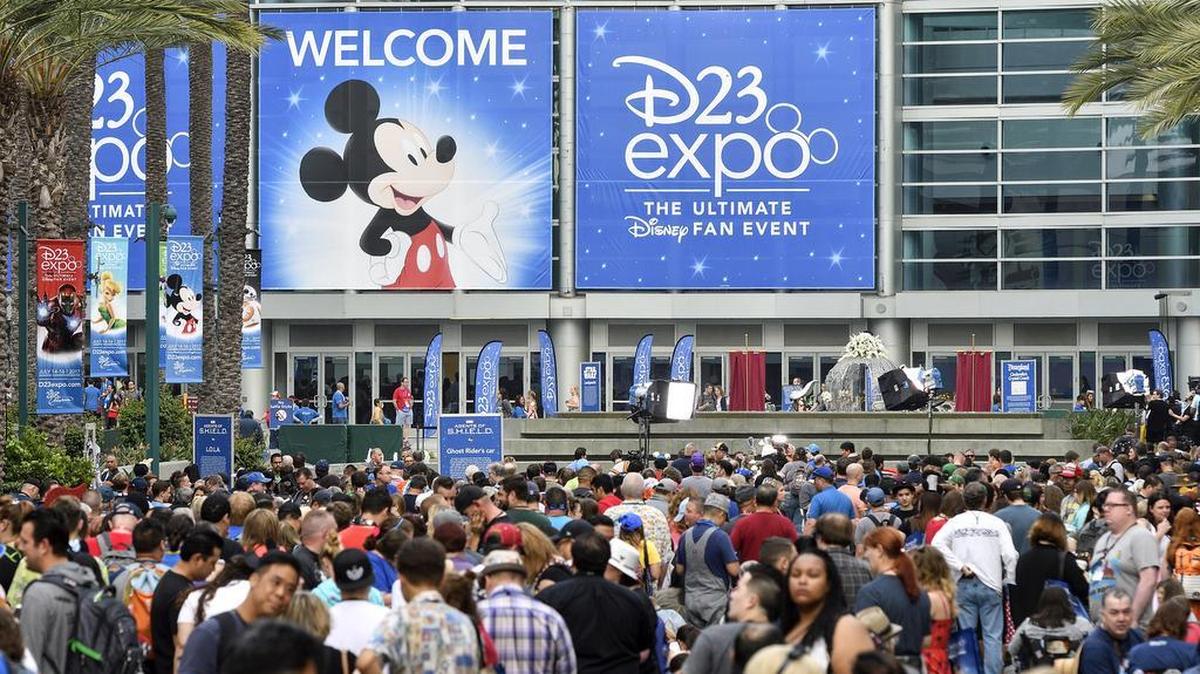 A crowd of people wait to enter the D23 Expo as crews do interviews outside the Anaheim Convention Center in Anaheim, Calif., on Friday, July 14, 2017.
