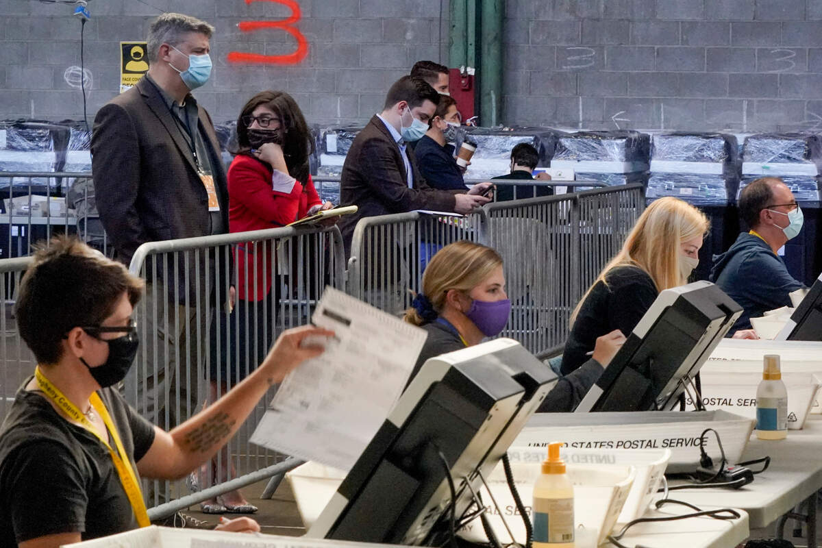 Election observers stand behind a barrier and watch as election office workers process ballots as counting continues from the general election at the Allegheny County elections returns warehouse in Pittsburgh, Friday, Nov. 6, 2020. (AP Photo/Gene J. Puskar)