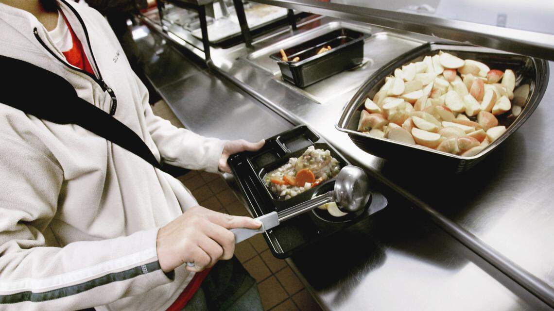 In this Nov. 19, 2007, file photo, a student puts apple slices on his tray during lunch. A Louisiana woman posed as a provider for the Child and Adult Care Food Program which provides reimbursements for meals served to eligible children and adults. The woman never served any meals but lied to pocket over $100,000 from the U.S. government, court documents show.