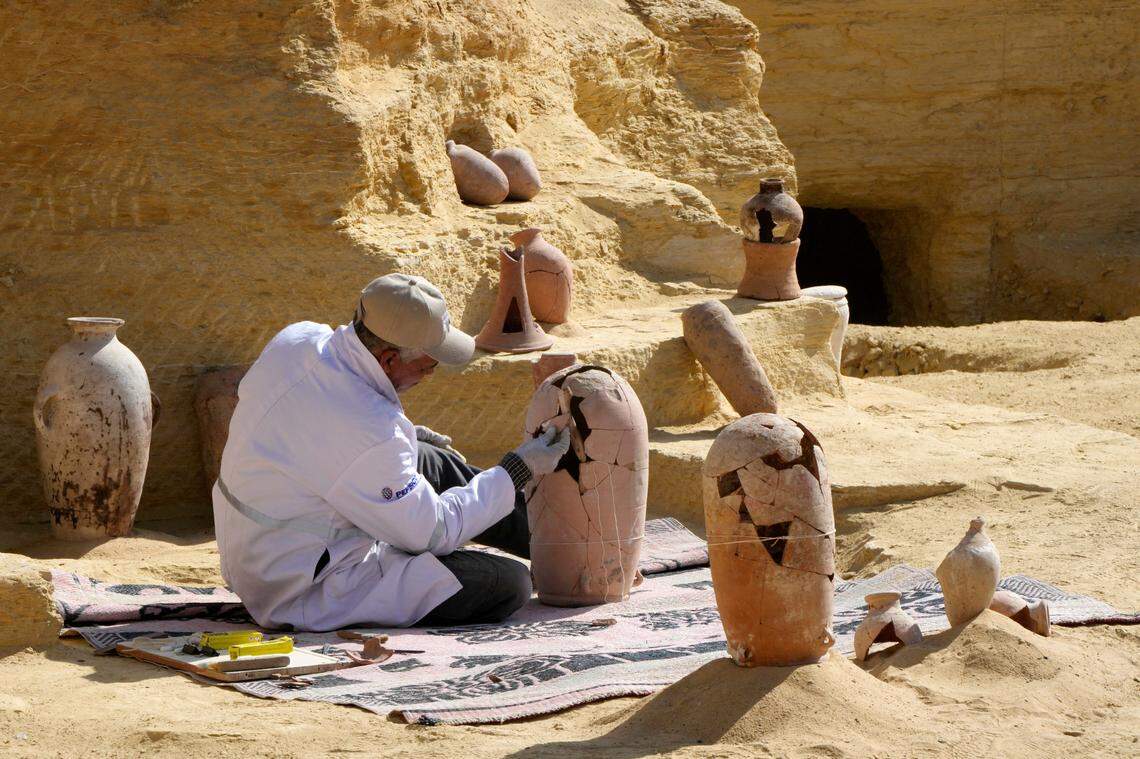 An Egyptian archeologist restores a recently discovered pottery at the site of necropolis. (AP Photo/Amr Nabil)