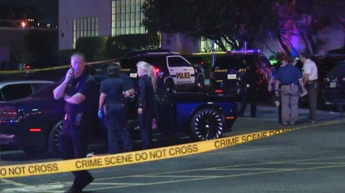 San Antonio police investigators surround a Dodge Charger in the parking lot of AllStars Gentleman's Club, where an off-duty police officer was shot six times after a road rage incident.
