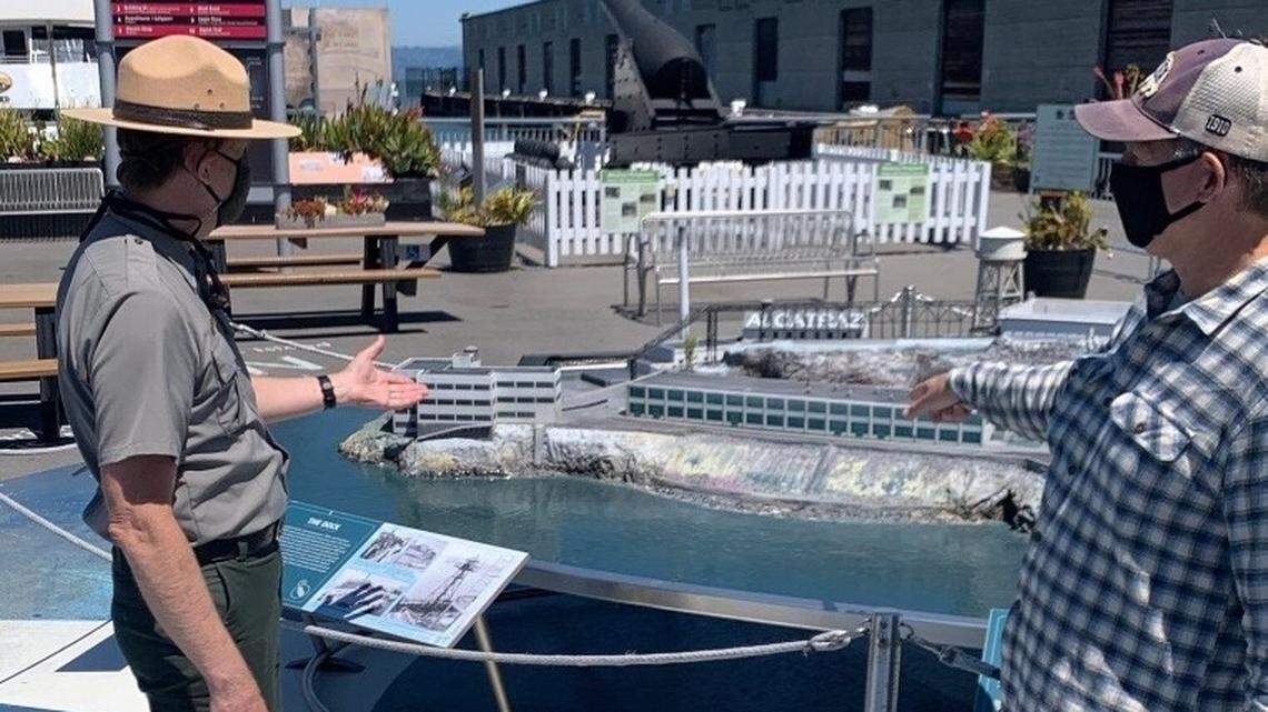 A staff member gestures to a model of Alcatraz Island at the ferry landing in San Francisco.