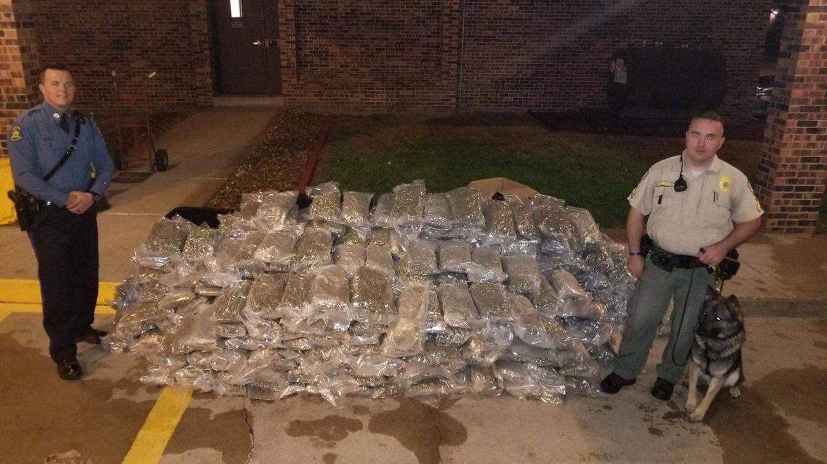 MIssouri Highway Patrol Trooper Jeff Maudlin, left, Buchanan County Sheriff’s Department Cpl. Vince Lippincott and Shadow, Lippincott’s K9 partner, pose for a photo with the 514 pounds police say were seized from Ricky Allan Martin’s Chevrolet Suburban.