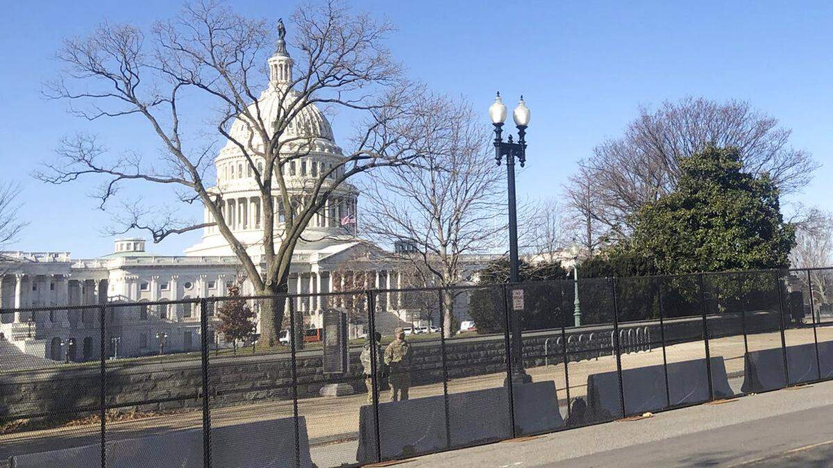 Members of the National Guard stand inside anti-scaling fencing that surrounds the Capitol, Sunday, Jan. 10, 2021, in Washington. (AP Photo/Alan Fram)