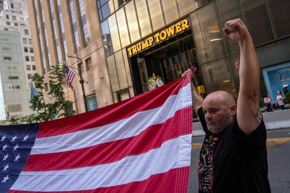 A supporter of former President Donald Trump helps to unfurl an oversized United States flag outside Trump Tower in midtown Manhattan on Sunday morning, July 14, 2024, one day after Trump was shot while speaking at a campaign rally in Butler, Pa. Trump was declared ÒfineÓ by his campaign, and the gunman was killed by Secret Service snipers. The explosion of political violence further inflamed the campaign for the White House. (Adam Gray/The New York Times)