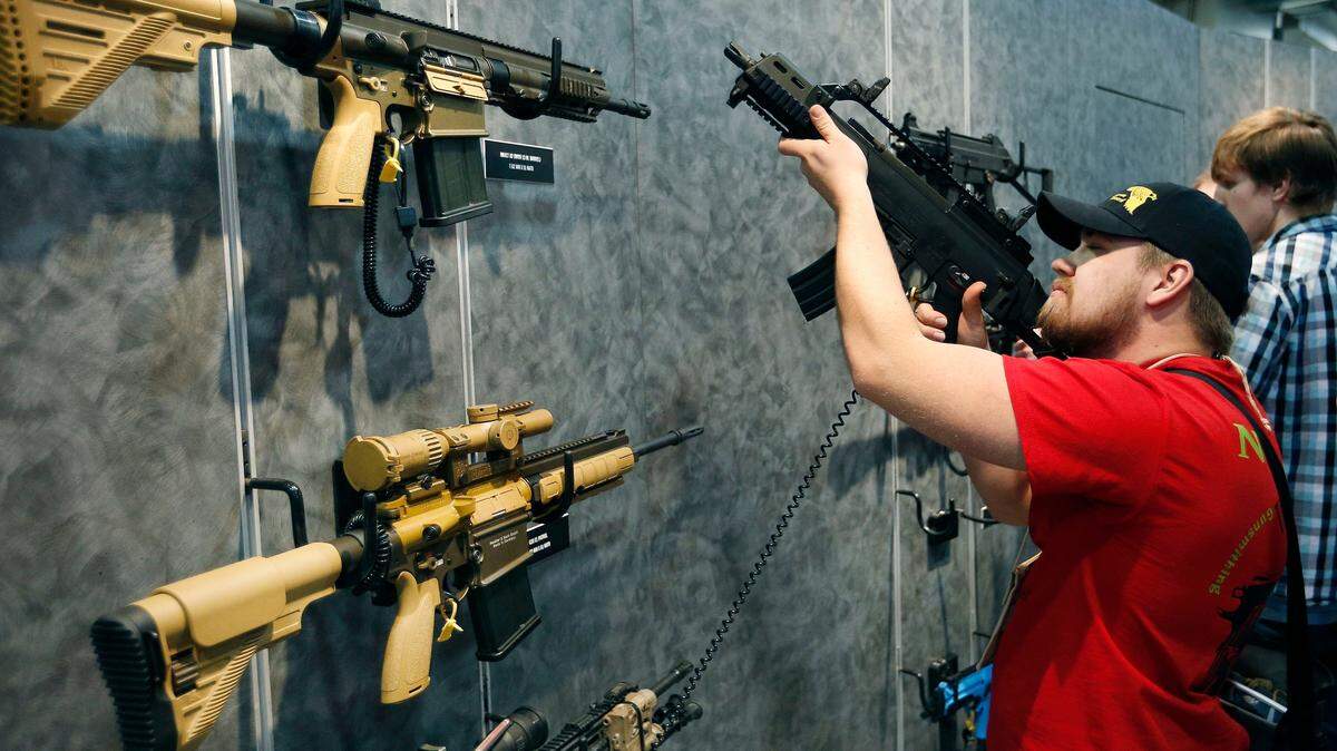 FILE - In this Jan. 19, 2016 file photo, customers look at a gun at the Heckler & Koch booth at the Shooting, Hunting and Outdoor Trade Show in Las Vegas. On Nov. 24, 2022, President Biden spoke in favor of an assault weapons ban. (AP Photo/John Locher, File)