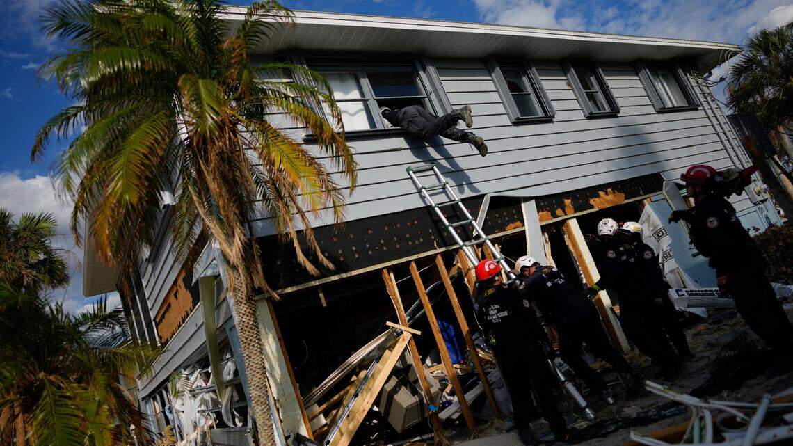 Members of Florida Task Force 2 urban search and rescue gain access to a home through a broken upper window to confirm the home is clear of people and human remains, a week after the passage of Hurricane Ian, in Fort Myers Beach, Fla., on Oct. 5, 2022.