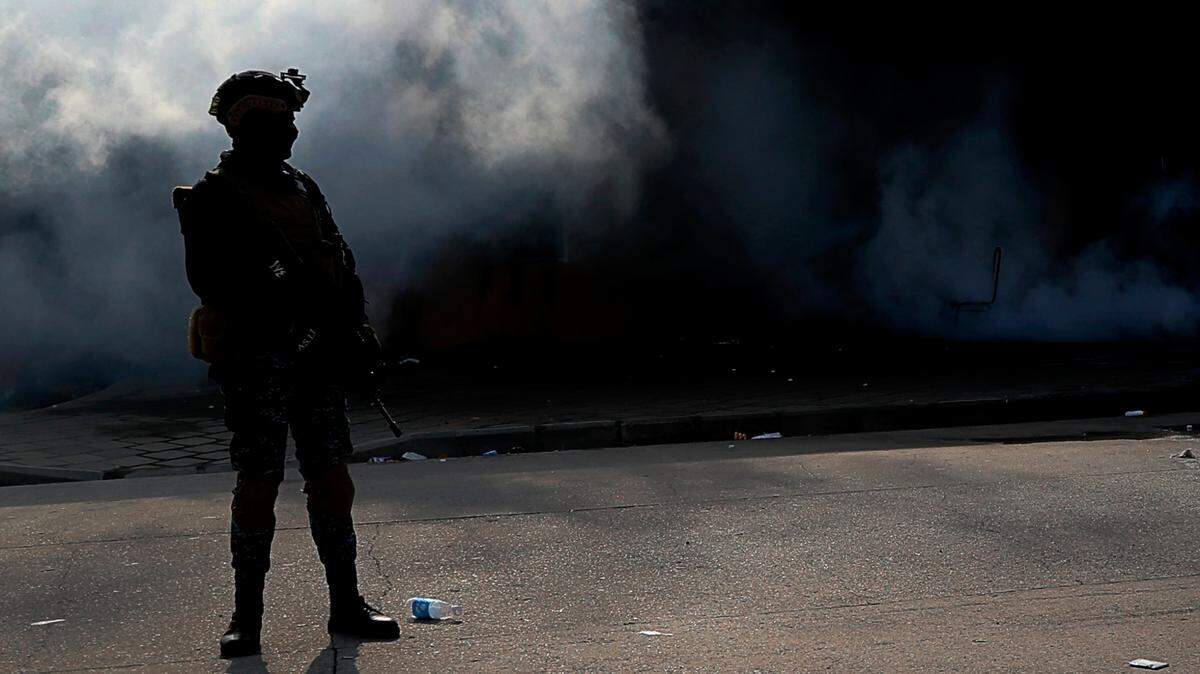 An Iraqi soldier stands guard in front of the U.S. Embassy in Baghdad while firefighters work on putting out a fire set by pro-Iranian militiamen and their supporters on Jan. 1, 2020.