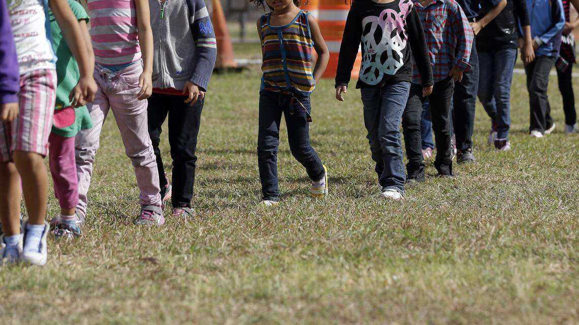 In this June 18, 2014, pool file photo, detainees walk in a line at a U.S. Customs and Border Protection processing facility in Brownsville, Texas.