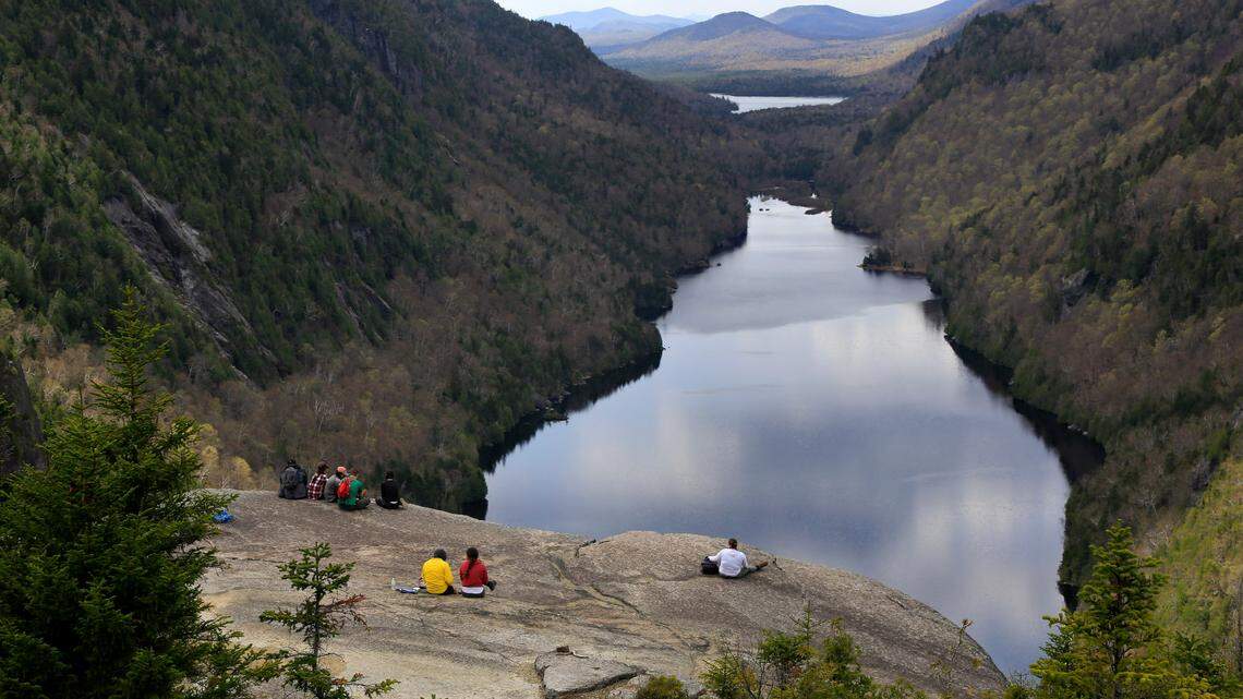 Hikers take in the view of Lower Ausable Lake from Indian Head Summit, Saturday, May 15, 2021, at the Adirondack Mountain Reserve near St. Huberts, N.Y. Rangers in the Adirondack Mountains found the body of a hiker who went missing on March 11, 2022. (AP Photo/Julie Jacobson)
