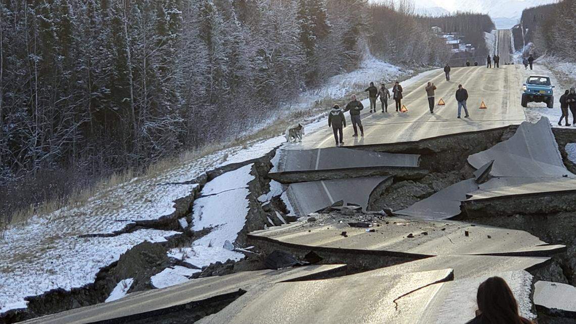 People walk along Vine Road in Wasilla, Alaska, after an earthquake on Nov. 30, 2018. State troopers have now warned locals not to take selfies or explore the unsafe stretch of road.