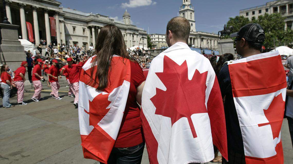People draped in Canadian flags in central London’s Trafalgar Square on Canada Day.