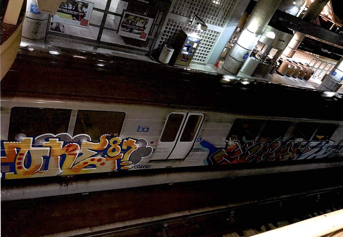 BART trains tagged with graffiti shown from above at a station.