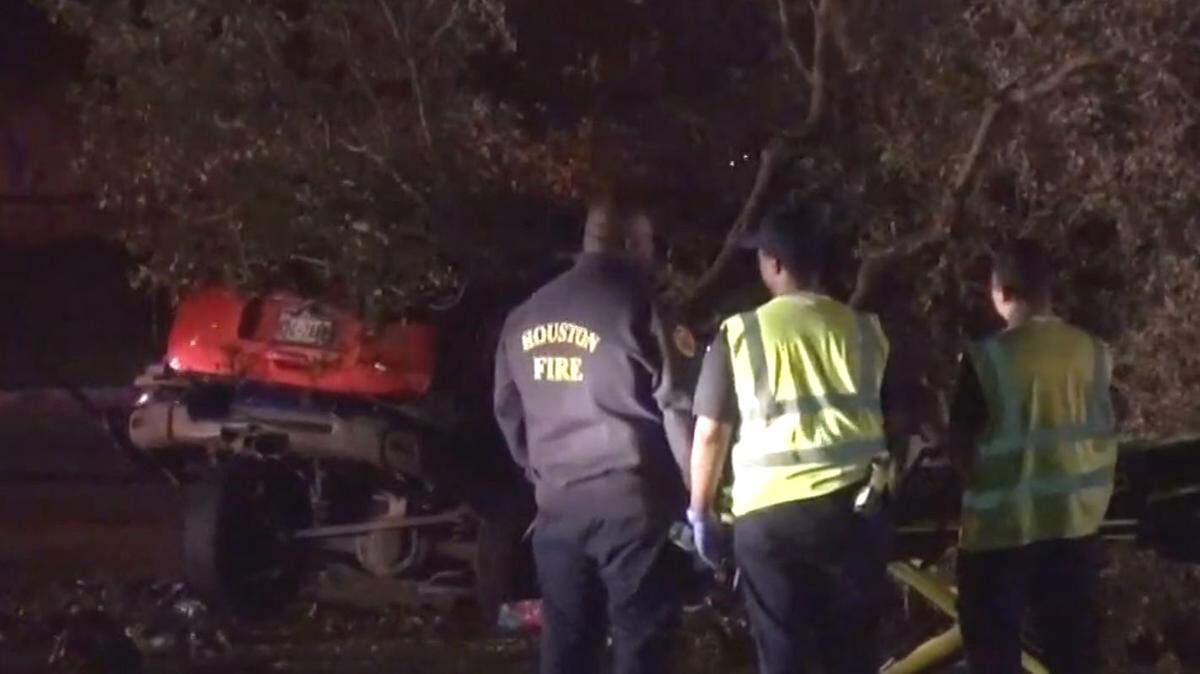 Investigators look on while the scene in southwest Houston is cleared early Wednesday after a street-racing crash.