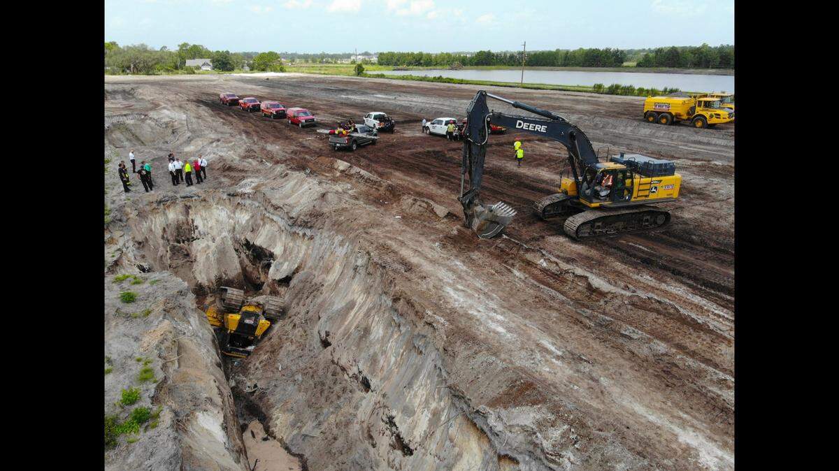 A bulldozer flipped over a 20-foot embankment at a construction site, pinning in the driver for 45 minutes, Florida officials said.