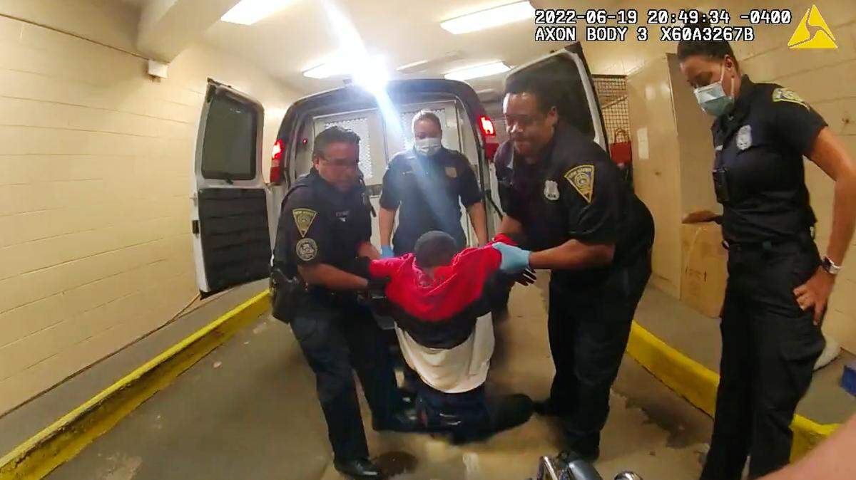 In this image taken from police body camera video provided by New Haven Police, Richard “Randy” Cox, center, is pulled from the back of a police van and placed in a wheelchair after being detained by New Haven Police on June 19, 2022, in Connecticut. Cox’s lawyers filed a $100 million lawsuit against the city on Sept. 27.