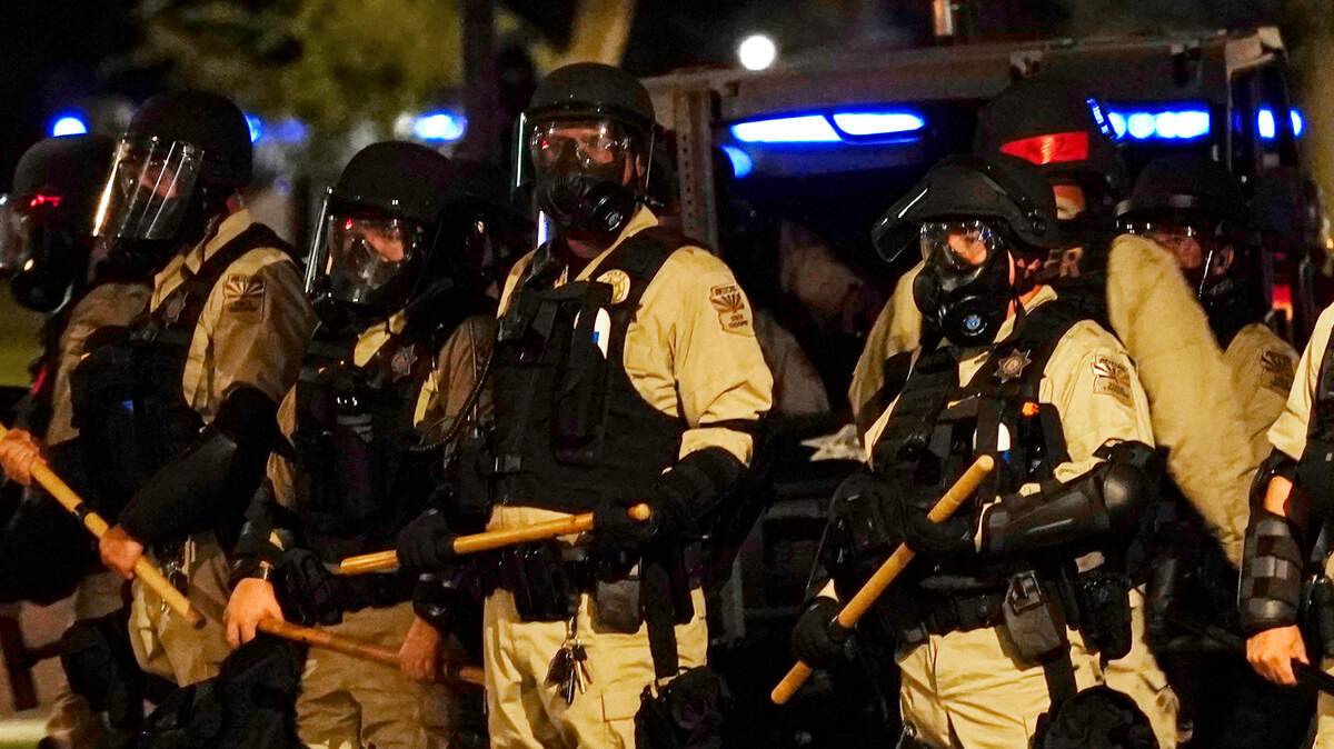 Police in riot gear surround the Arizona Capitol as people arrive to protest the Supreme Court decision to overturn the landmark Roe v. Wade abortion decision Friday, June 24, 2022, in Phoenix. A bill signed into law on July 6 will soon ban Arizonans from filming police officers at a distance closer than 8 feet. (AP Photo/Ross D. Franklin)