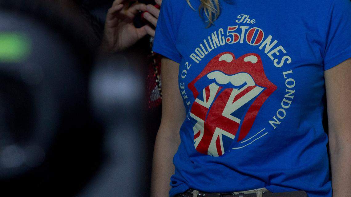 Fans of The Rolling Stones watch them perform at the O2 arena in east London, Sunday, Nov. 25, 2012. A California business that prints merchandise clothing for music giants such as the Rolling Stones, Britney Spears, Lady Gaga or Ariana Grande cheated 76 of its workers out of more than a hundred thousands of dollars of overtime pay, labor department officials say.