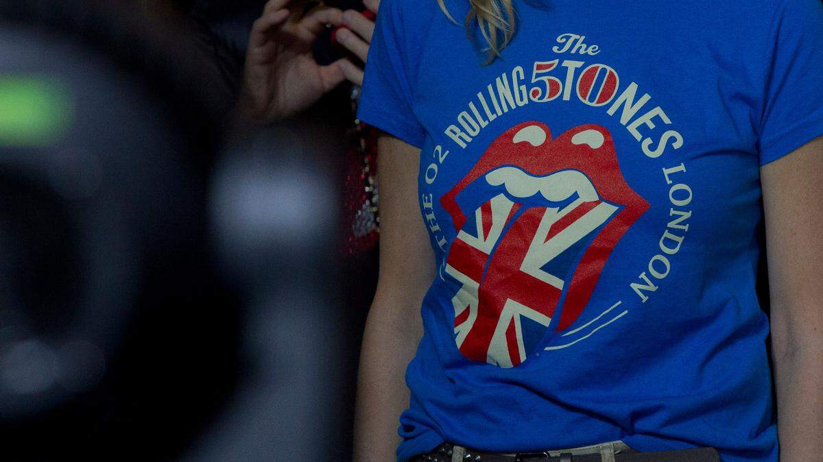 Fans of The Rolling Stones watch them perform at the O2 arena in east London, Sunday, Nov. 25, 2012. A California business that prints merchandise clothing for music giants such as the Rolling Stones, Britney Spears, Lady Gaga or Ariana Grande cheated 76 of its workers out of more than a hundred thousands of dollars of overtime pay, labor department officials say.