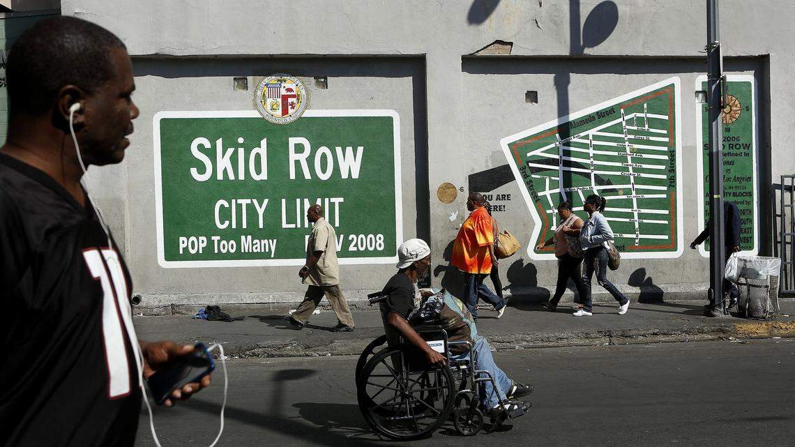 People make their way down the street in front of the wall mural on San Julian Street in the heart of Skid Row in downtown Los Angeles.