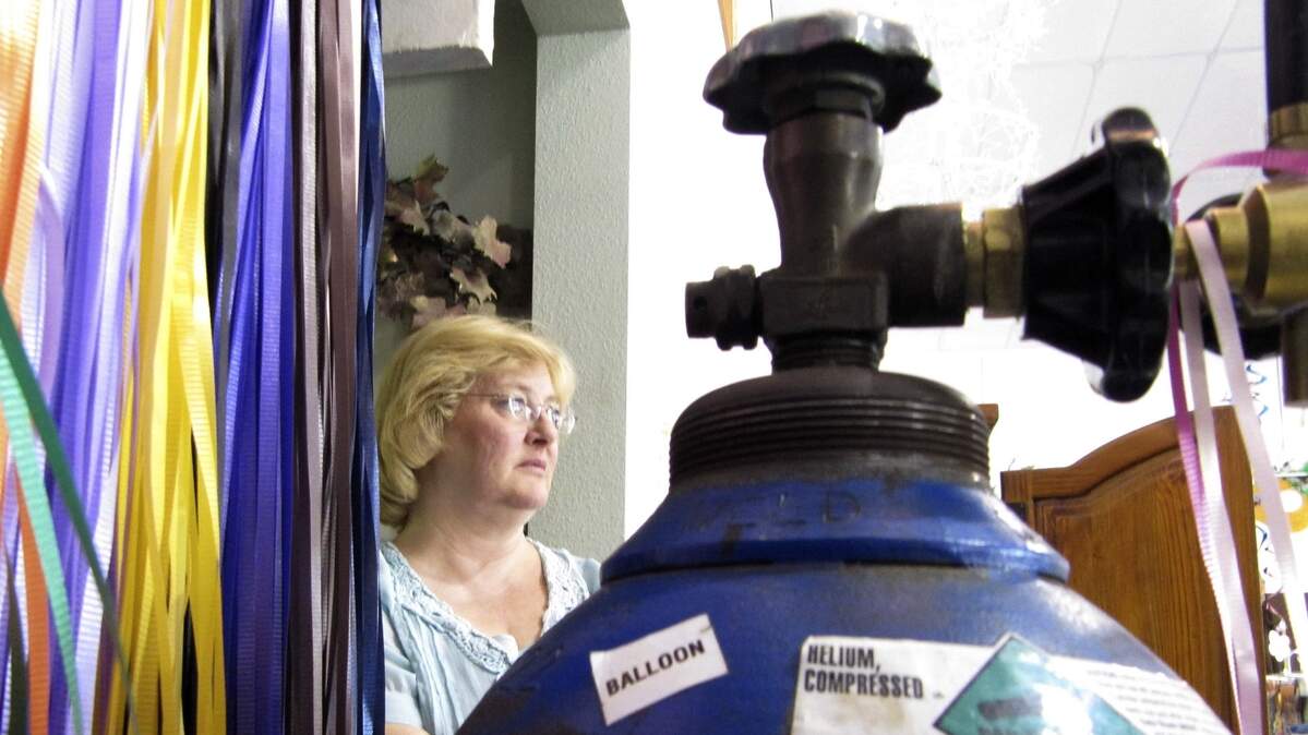 An employee at Dan D Party Corner in Cheyenne, Wyo., Lee Medina, stands near a close-to-empty helium tank used to fill balloons.