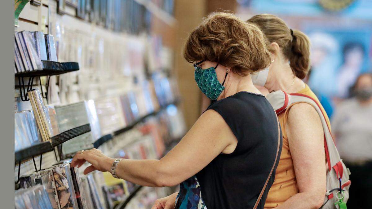 Judy Gallagher wears a mask as she looks through music at the Ernest Tubb Record Shop in June 2020 in Nashville. In 2021, CD sales increased for the first time in almost two decades.