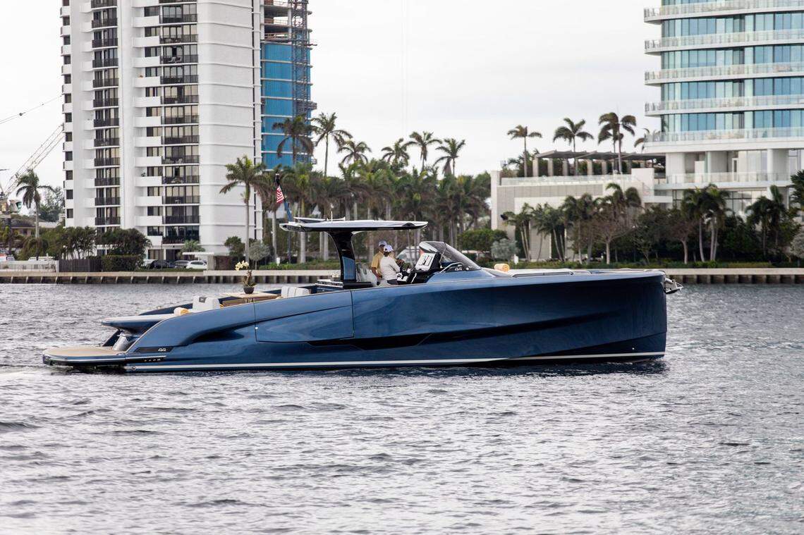 The BC One, a 44-foot yacht available to guests at The Brazilian Court, cruises along the water with Palm Beach, Florida, hotels in the background.