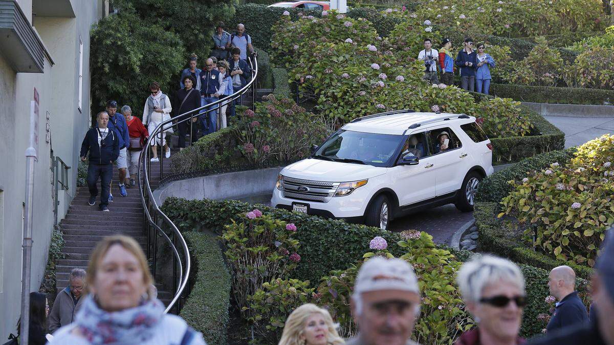 Tourists make their way down Lombard Street, also known as the “most crooked street” in San Francisco.