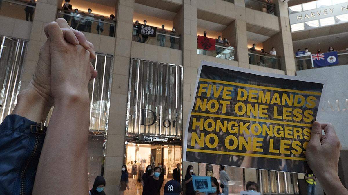 A protestor raises a placard during a protest at a shopping mall in Hong Kong, Wednesday, April 29, 2020. Demonstrators gathered in a luxury mall chanting pro-democracy slogans, the latest in a string of protests over the past week. (AP Photo/Vincent Yu)