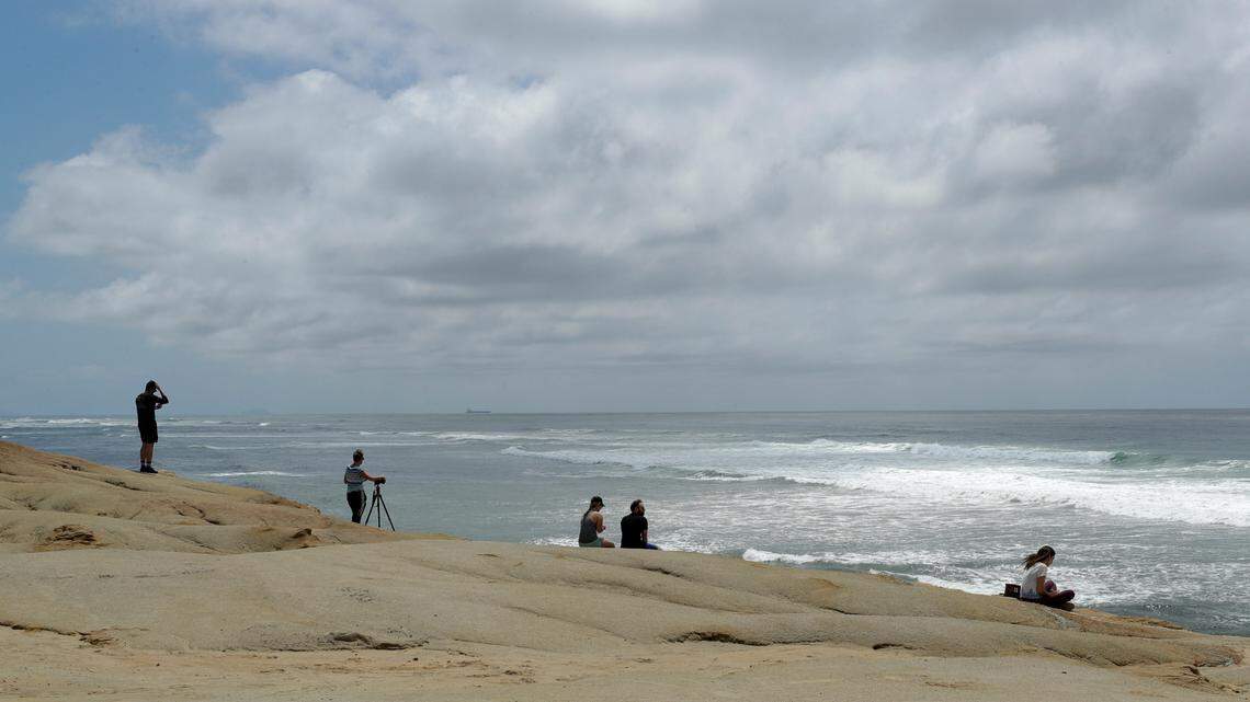 Visitors look out over the water at Sunset Cliffs Natural Park after portions of the park opened Tuesday, April 21, 2020, in San Diego. A man was rescued half a mile from the coast after nearby residents heard him crying for help and called authorities. (AP Photo/Gregory Bull)