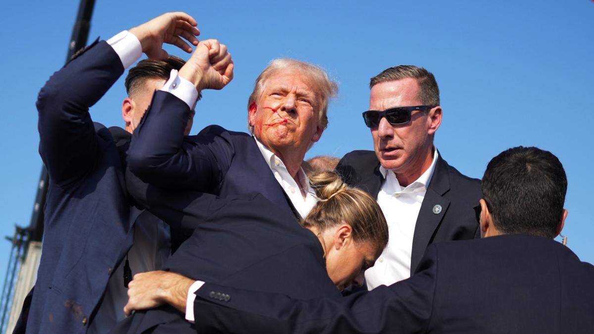 Former President Donald Trump is surrounded by Secret Service agents at a campaign rally in Butler, Pa, on Saturday, July, 13, 2024. Trump was escorted off the stage by Secret Service agents and into his motorcade just minutes into his rally in Butler, Pa., on Saturday, after a series of pops that sounded like gunshots rang out. (Doug Mills/The New York Times)