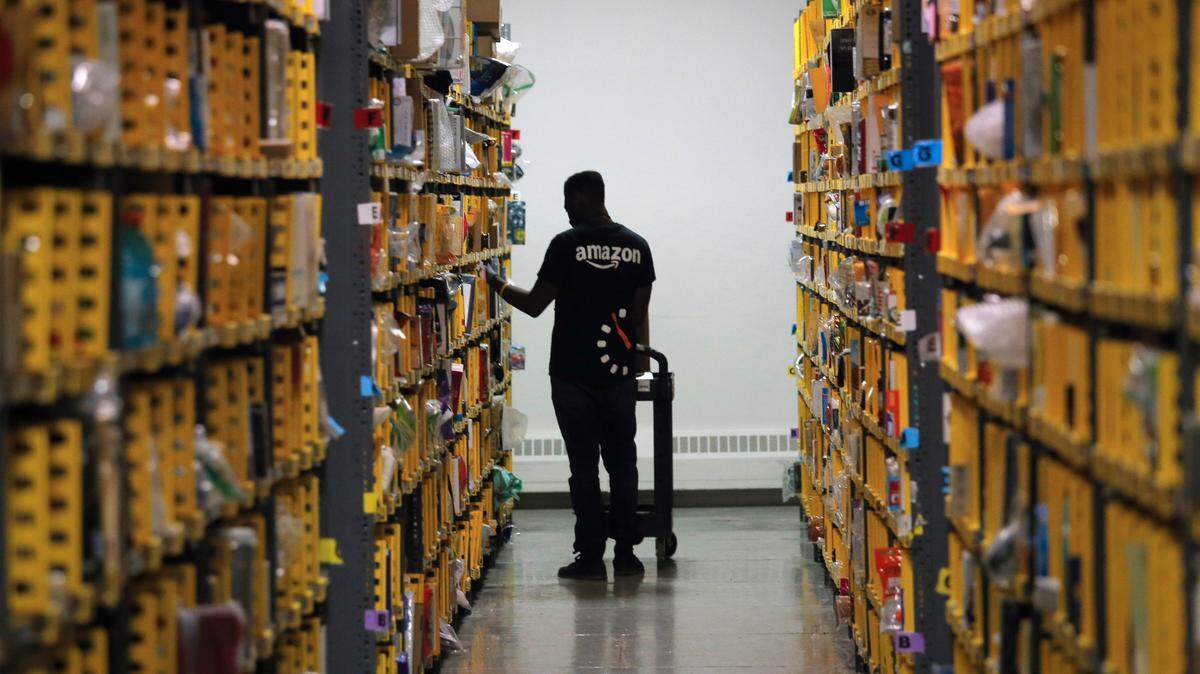 An employee of Amazon PrimeNow stacks shelves at a distribution hub in New York in December 2016. Amazon announced on April 13 that it will now charge sellers a 5% fuel and inflation surcharge to offset rising costs. The fee could mean higher prices for consumers.