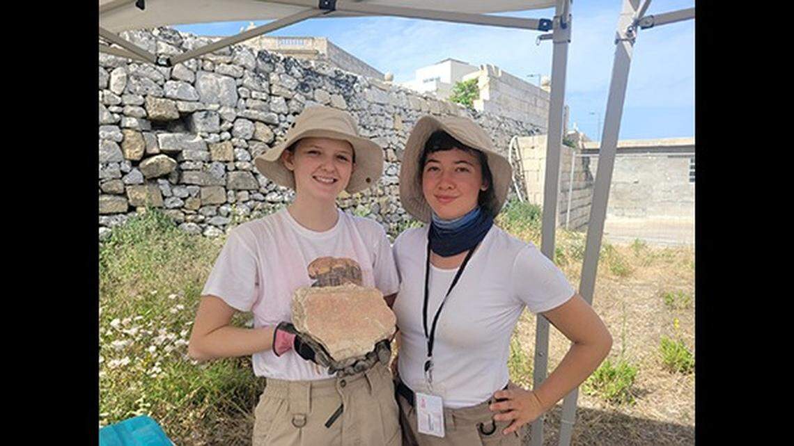 Team members with a piece of plastered frescoe excavated from the site in Malta.