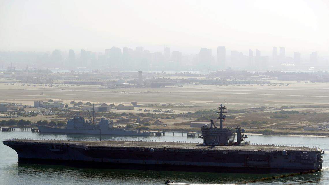 FILE - In this July 9, 2020 file photo the USS Theodore Roosevelt aircraft carrier makes its way into San Diego Bay as seen from San Diego. Three sailors aboard the USS Theodore Roosevelt have tested positive for COVID-19, the Navy said Monday, Feb. 15, 2021, less than a year after a massive outbreak on the ship sidelined it in Guam for nearly two months. (AP Photo/Gregory Bull, File)