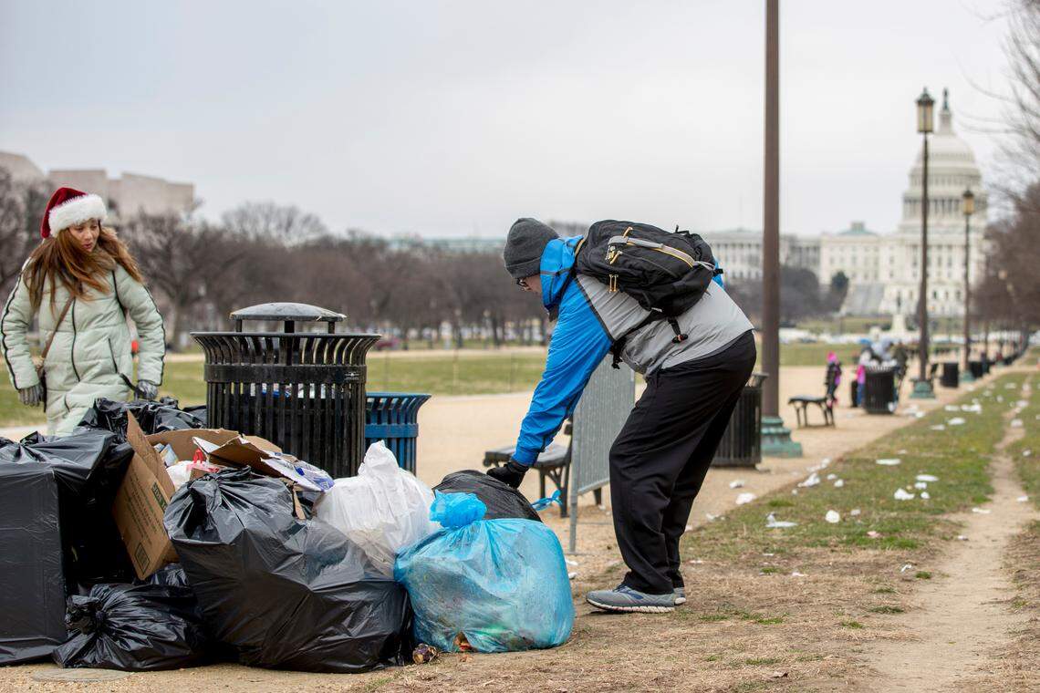 The Capitol building is visible as a man who declined to give his name picks up garbage and stacks it near a trash can during a partial government shutdown on the National Mall in Washington.