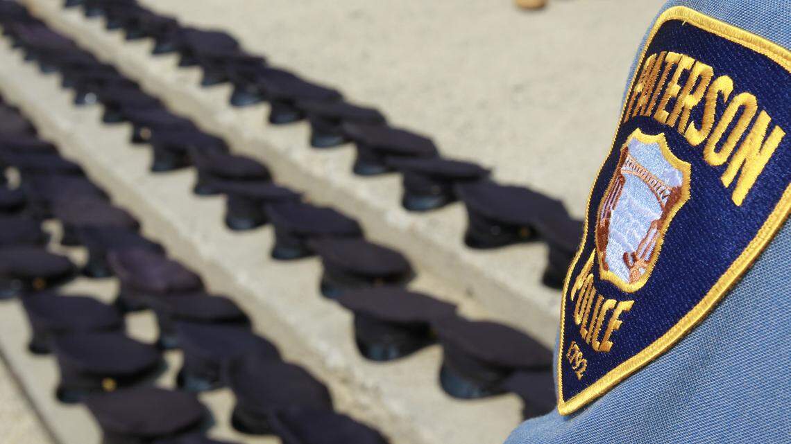 The badge of an active Paterson Police Department officer is seen as police hats are arranged in a line outside of the public safety complex building during a protest by laid-off officers from the Paterson Police Department in Paterson, N.J. on Monday, April 18, 2011. (AP Photo/Julio Cortez)