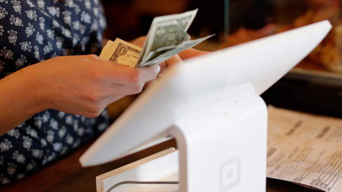 An employee counts cash given to her by a customer in this 2015 photo. A South Carolina restaurant forced 92 employees to contribute to an illegal tip pool that included managers, according to labor department officials.