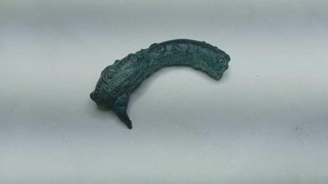 A bronze snake head was among the artifacts found at the site.