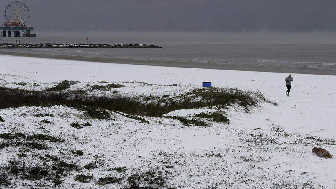 A jogger run along the snow covered beach near 37th Street in Galveston, Texas on Monday, Feb. 15, 2021. (Jennifer Reynolds/The Galveston County Daily News via AP)