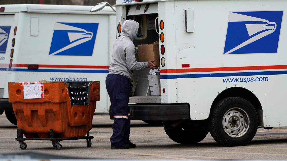 A USPS employee loads a truck outside post office on Dec. 3, 2021. A former postal worker who claimed to injure his back while working at USPS received over $730,000 in disability payments for a decade, prosecutors said. During these years, the man was caught hiking, fishing, riding bikes, traveling and weightlifting and is now going to prison.