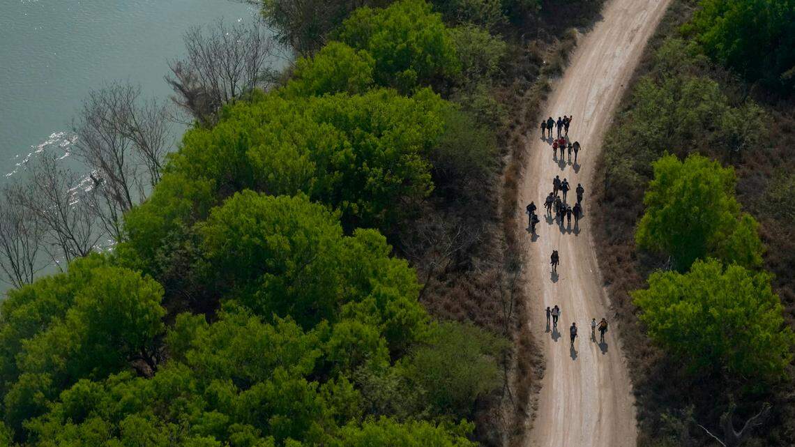 Migrants walk on a dirt road along the Rio Grande in Mission, Texas, on March 23, 2021, after crossing the U.S.-Mexico border. A group of seven migrants was held against their will at a house in Harlingen, Texas, about 42 miles east of Mission. (AP Photo/Julio Cortez)