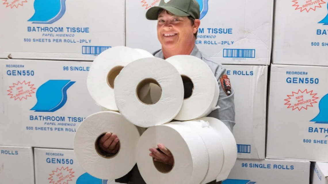 A park employee holds multiple rolls of toilet paper at Yellowstone National Park.