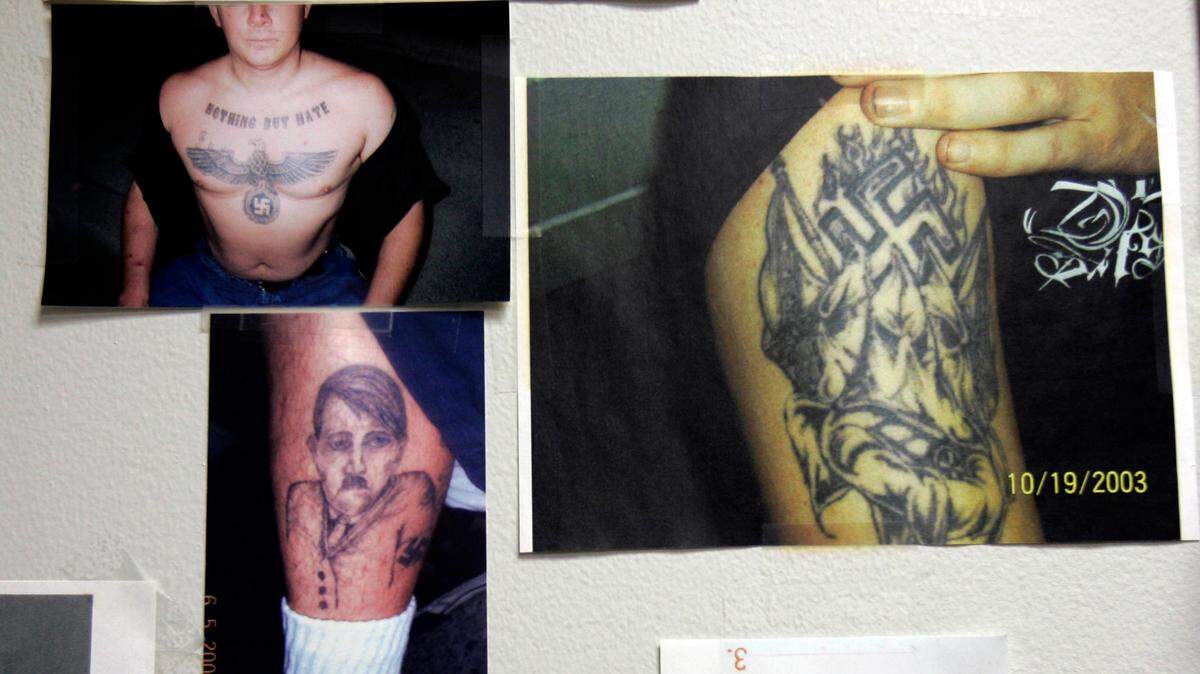 Photographs showing neo-Nazi and gang tattoos hang in the gang unit office at the police station in Buena Park, Calif., Feb. 24, 2007. (AP Photo/Ann Johansson)