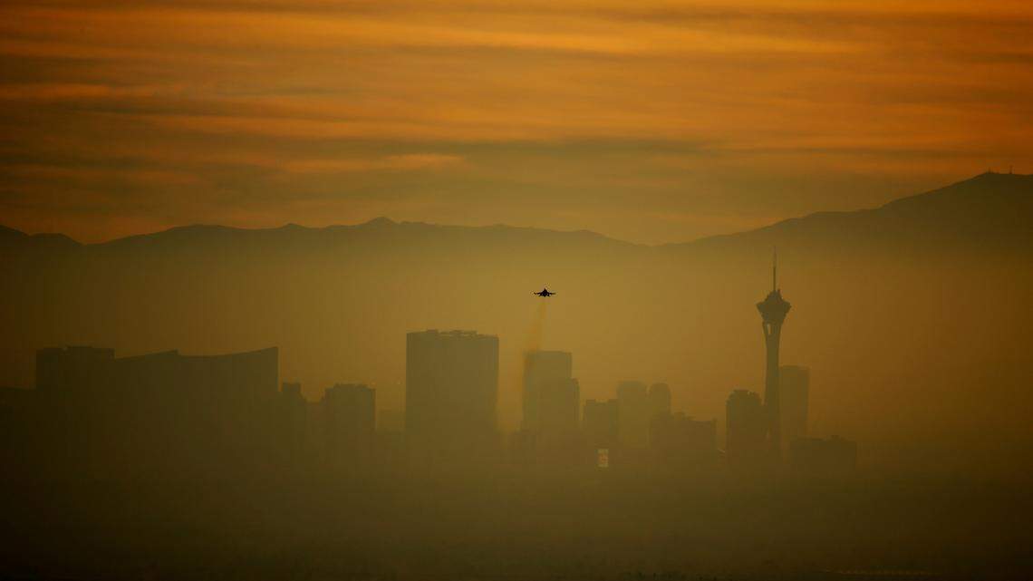 A plane takes off from Nellis Air Force Base as the sun sets over a hazy Las Vegas skyline on Wednesday, Dec. 9, 2015. A man was arrested in Las Vegas on July 20, 2022 after being accused of leaving a puppy inside a hot car as he went to gamble. (AP Photo/John Locher)