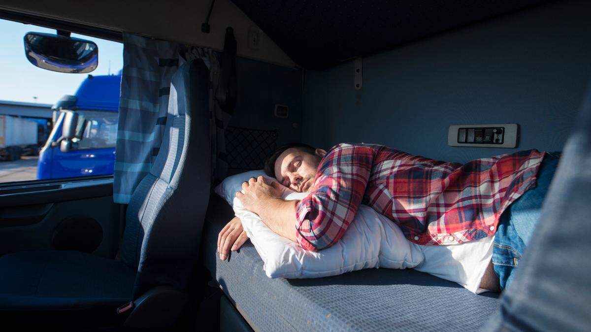 Truck driver sleeping in his cabin, presumably just after getting off the road.