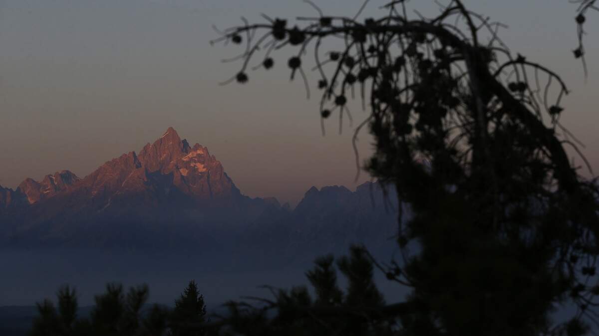 The sun at dawn illuminates mountain peaks, partially obscured by haze from the wildfires nearby as seen from Signal Mountain in Grand Teton National Park, Wyo., Aug 25, 2016. Aug 25, 2016 marked the 100th anniversary of the US National Park Service. (AP Photo/Brennan Linsley)