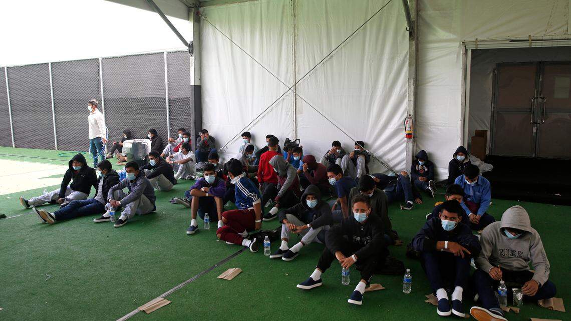 Minor children who tested positive for COVID-19 sit in the ground at the Donna Department of Homeland Security holding facility, the main detention center for unaccompanied children in the Rio Grande Valley run by U.S. Customs and Border Protection (CBP), in Donna, Texas, Tuesday, March 30, 2021. The Biden administration on Tuesday for the first time allowed journalists inside its main detention facility at the border for migrant children, revealing a severely overcrowded tent structure where more than 4,000 kids and families were crammed into pods and the youngest kept in a large play pen with mats on the floor for sleeping.(AP Photo/Dario Lopez-Mills, Pool)