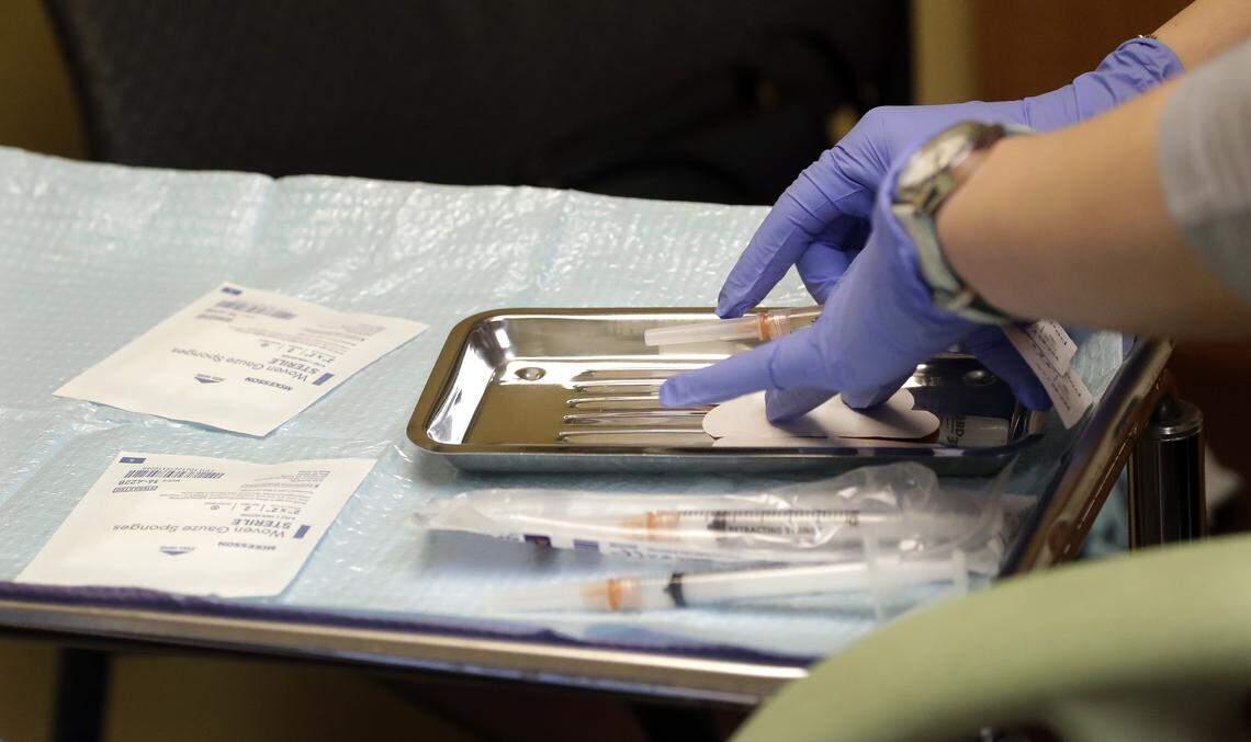 A health care worker prepares syringes, including a vaccine for measles, mumps, and rubella (MMR), for a child’s inoculations at the International Community Health Services Wednesday in Seattle.