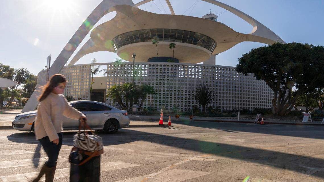 A traveler walks past The Theme Building at Los Angeles International Airport in Los Angeles, Wednesday, Nov. 25, 2020. The FBI recently announced a new theory to explain sightings of what looked like a man in a jetpack flying over Los Angeles. (AP Photo/Damian Dovarganes)