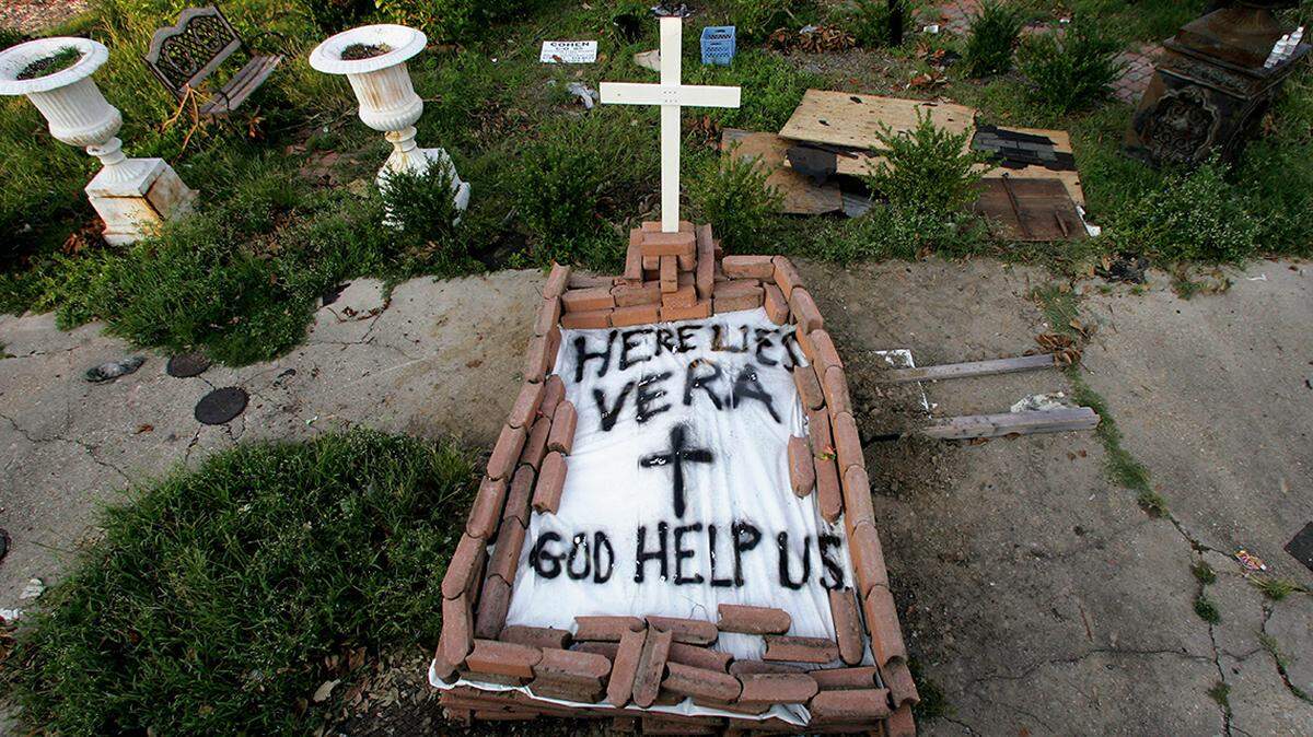 FILE - In this Sept. 4, 2005, file photo, a makeshift tomb at a New Orleans street corner conceals a body that had been lying on the sidewalk for days in the wake of Hurricane Katrina. The message reads, “Here lies Vera. God help us.” Smith’s cremated remains were later reburied in Texas, yet she remains part of her old community. (AP Photo/Dave Martin, File)